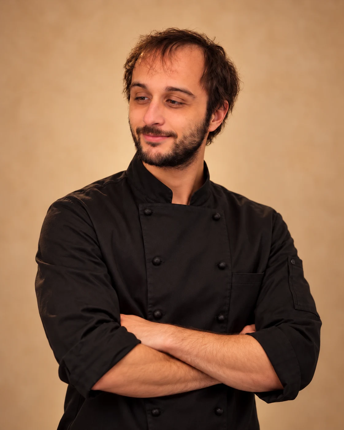 Portrait d’Anthony sur fond beige, en tenue noire